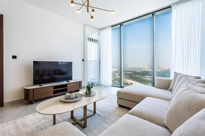 a living room with a couch and a tv at Elegant 2-Bedroom Apartment with Stunning City and Water Views in Dubai