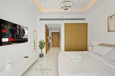 a white bedroom with a large bed and a tv at Estudio Sultan en Dubái por beBalmy in Dubai