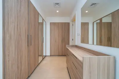a dressing room with wooden cabinets and a mirror at Dubai Hills Townhouse in Dubai