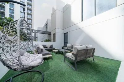 an outdoor patio with chairs and a swing at Dubai Hills Townhouse in Dubai