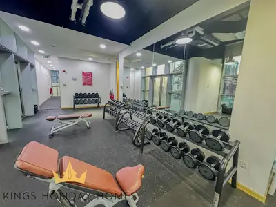 a gym with a row of benches and dumbbells at Central Park towers residence difc in Dubai