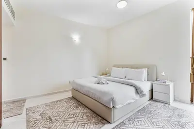 a white bedroom with a bed and a rug at 2-Bedroom Haven with Canal View near The Els Club in Dubai