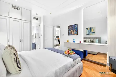 a white bedroom with a large bed and a table at Arabian Elegance 1BR Zanzabeel 1 Burj Khalifa View in Dubai