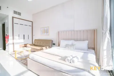 a white bedroom with a large bed and a couch at Elz Residence Stylish Studio Living in Dubai
