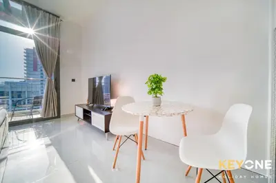 a dining room with a table and white chairs at Elz Residence Stylish Studio Living in Dubai