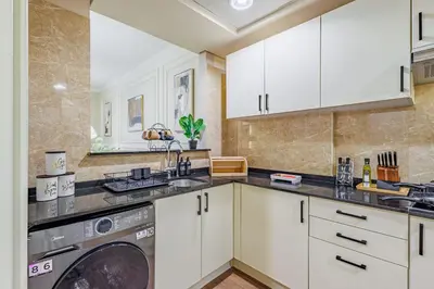 a kitchen with white cabinets and a washer and dryer at Elegant Oasis - 15 min to Burj Khalifa and Aiport - 1 BDR - 4 pax in Dubai