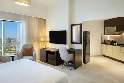 a hotel room with a bed and a desk with a television at Vintage Grand Hotel Apartments Dubai in Dubai
