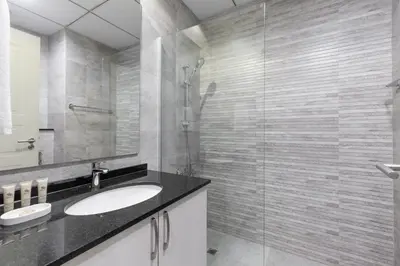 a bathroom with a sink and a glass shower at Maison Privee - Chic & Eclectic Family Home with Park Vws in Meydan in Dubai