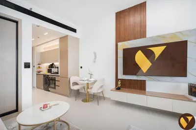 a living room with a table and a yellow painting on the wall at Vogue JVC Binghatti Dawn near Circle Mall, Studio Apartment with Balcony and Vibrant Community View, Access to all Amenities in Dubai