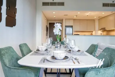 a dining room table with green chairs and a white table with glasses at Luxury 2BR Harbour Views Tower 2 Creek Harbour Dubai in Dubai