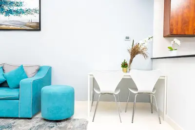 a living room with a blue couch and a table and chairs at Escape24 Elegant 1BR with Marina Views, Dubai Marina in Dubai
