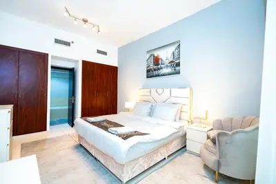 a white bedroom with a bed and a chair at Escape24 Elegant 1BR with Marina Views, Dubai Marina in Dubai