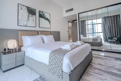 a bedroom with a large bed and a living room at TRPS - MAG 318, Business Bay - Pool View, 2BR Fully Furnished, Prime Location in Dubai