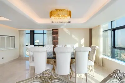 a dining room with white chairs and a chandelier at Samaya Holiday Homes - Square 1B Duplex Panoramic View in Dubai