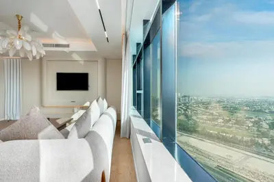 a living room with white furniture and a large window at Samaya Holiday Homes - Square 1B Duplex Panoramic View in Dubai