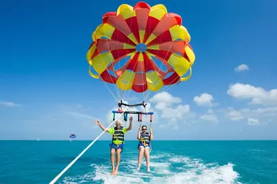 two people are standing in the water with a parachute at Parasailing Boat Dubai in Dubai