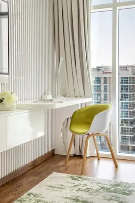 a green chair in a room with a window at Frank Porter - Glitz Residence 2 in Dubai