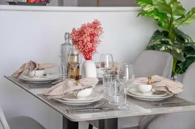 a table with plates and glasses and a vase with flowers at Frank Porter - Glitz Residence 2 in Dubai