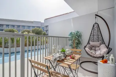 a balcony with a swing and a table and chairs at Frank Porter - Luma22 West Tower in Dubai