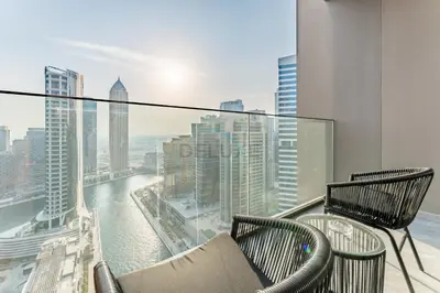 a balcony with two chairs and a view of the city at Studio with Dubai Canal View, Walking Distance to Metro Station and Near Downtown Dubai - Peninsula One, Business Bay by Deluxe Holiday Homes in Dubai
