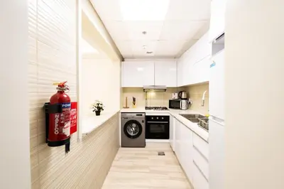 a kitchen with a washing machine and a fire extinguisher at Escape24 Elegant 1BR in JVC with Pool View in Dubai
