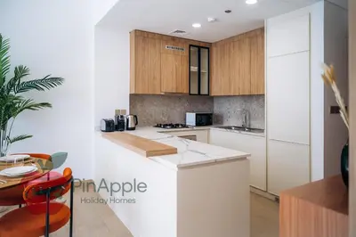 a kitchen with white counters and wooden cabinets at Beautiful Brand New Spacious in Dubai