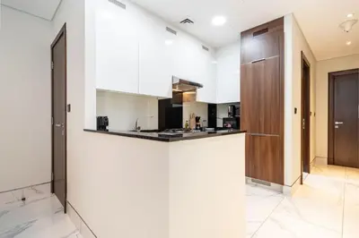 a kitchen with white walls and a wooden door at Chic and Urban 1-Bed Business Bay Suite in Dubai