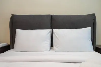 a bed with two white pillows and a gray headboard at Chic and Urban 1-Bed Business Bay Suite in Dubai