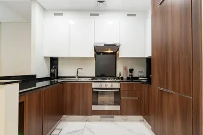 a kitchen with wooden cabinets and a stove top oven at Chic and Urban 1-Bed Business Bay Suite in Dubai