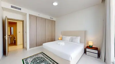 a white bedroom with a large white bed and a doorway at Vacationer l Serene 3 Bed Haven l Private Beach l District One in Dubai