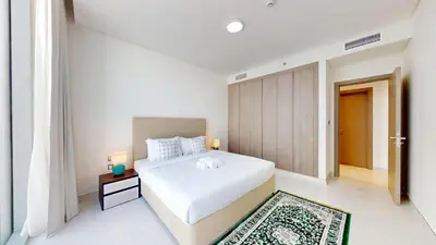 a white bedroom with a white bed and a door at Vacationer l Serene 3 Bed Haven l Private Beach l District One in Dubai