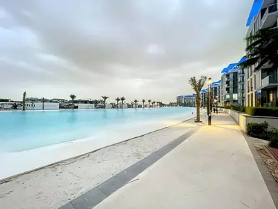 a pool at the beach with palm trees and buildings at Vacationer l Stunning 1 Bed l Private Beach l near Downtown in Dubai