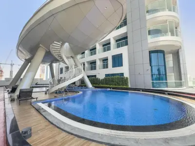a building with a swimming pool in front of a building at Vacationer I Premium Studio I Pool & Gym Access I Near Miracle Garden I Opalz Tower 2 in Dubai