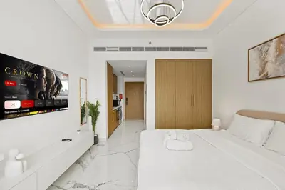 a white bedroom with a large bed and a tv at Estudio Rimal en Dubái por beBalmy in Dubai