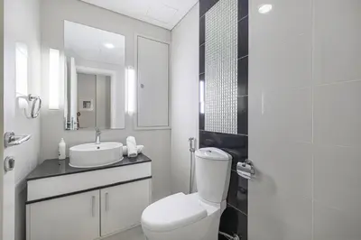 a white bathroom with a toilet and a sink at Burj Khalifa view - 2 BR apartment in Downtown in Sabkhah