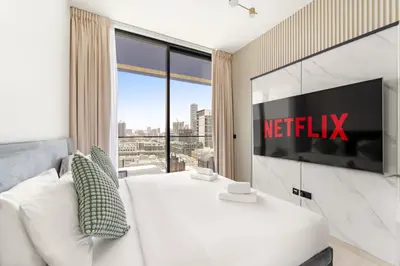 a bedroom with a television and a white couch at VayK - Gorgeous 1BR Retreat in Binghatti Corner in Dubai