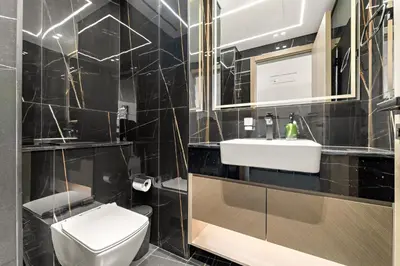 a black tiled bathroom with a toilet and a sink at VayK - Gorgeous 1BR Retreat in Binghatti Corner in Dubai