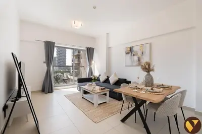 a living room with a table and a couch at Vogue JVC Jeewar Tower near Circle Mall, One Bedroom Apartment with Balcony and Park view, Access to all Amenities in Dubai