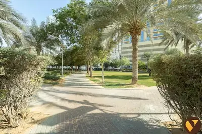 a street with palm trees in front of a building at Vogue JVC Jeewar Tower near Circle Mall, One Bedroom Apartment with Balcony and Park view, Access to all Amenities in Dubai