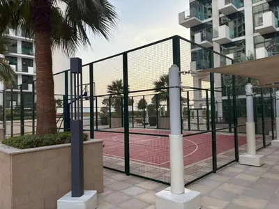 a tennis court behind a fence with a net at Deluxe studio water front in Dubai