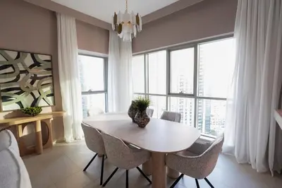 a dining room with a table and chairs and windows at Luxury Family Friendly Apartment - Full Burj Khalifa & Fountain Views in Dubai