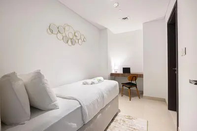 a white bedroom with a bed and a desk at Downtown Views By Luxe Living - Full Burj Khalifa Views in Dubai