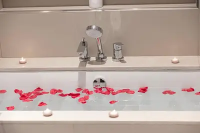 a bathroom sink with red flowers on a counter at Downtown Views By Luxe Living - Full Burj Khalifa Views in Dubai