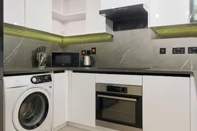 a white kitchen with a washer and a microwave at Modern & Cozy 1BR Apartment | Dubai Eye View in Dubai