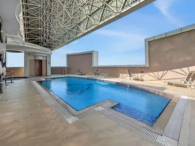 a large swimming pool in a building at Serene 1BR with Balcony & Pool in Siraj Tower in Dubai