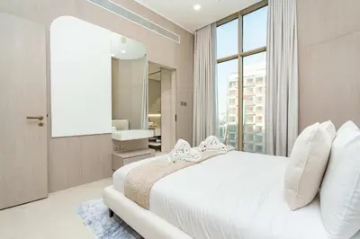 a bedroom with a white bed and a bathroom at PVH - Sleek 1BR near Community Park - Pearl House 1 in Dubai