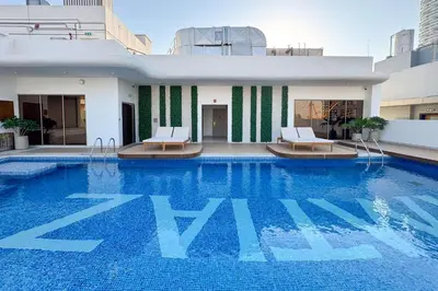 a swimming pool with two chairs and a building at PVH - Sleek 1BR near Community Park - Pearl House 1 in Dubai