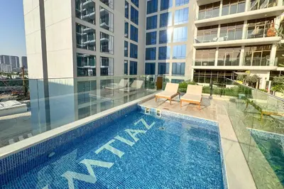 a swimming pool with two chairs next to a building at PVH - Sleek 1BR near Community Park - Pearl House 1 in Dubai