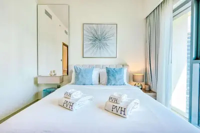 a bedroom with a large white bed with blue pillows at PVH - Charming 1BR near Dubai Mall - Burj Royale in Dubai