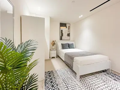 a white bedroom with a bed and a plant at Contemporary Luxe Stay at Dawn by Binghatti! in Dubai